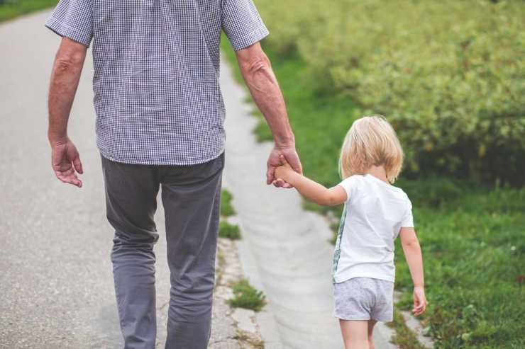 Adult and child holding hands while walking.